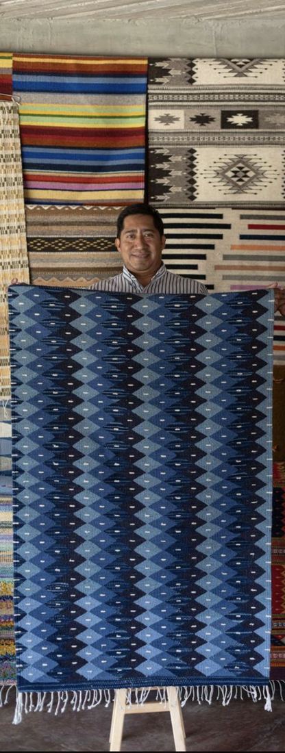 Hilario sosteniendo uno de sus tapetes, en su taller de Teotitlán del Valle